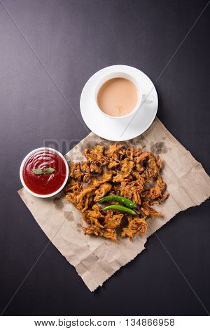 Crispy onion bhaji or kanda bhaji or fried onion pakore or pakode, delicious street food, favourite indian snack in monsoon served with hot tea