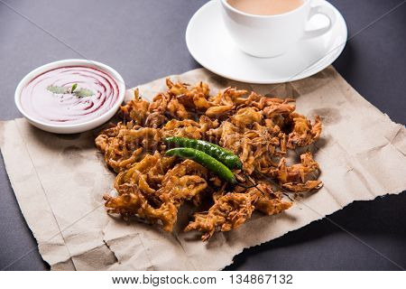 Crispy onion bhaji or kanda bhaji or fried onion pakore or pakode, delicious street food, favourite indian snack in monsoon served with hot tea