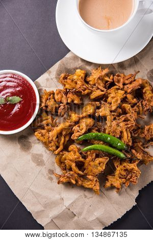 Crispy onion bhaji or kanda bhaji or fried onion pakore or pakode, delicious street food, favourite indian snack in monsoon served with hot tea