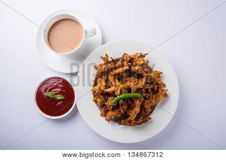 Crispy onion bhaji or kanda bhaji or fried onion pakore or pakode, delicious street food, favourite indian snack in monsoon served with hot tea
