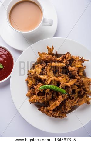 Crispy onion bhaji or kanda bhaji or fried onion pakore or pakode, delicious street food, favourite indian snack in monsoon served with hot tea
