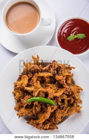 Crispy onion bhaji or kanda bhaji or fried onion pakore or pakode, delicious street food, favourite indian snack in monsoon served with hot tea