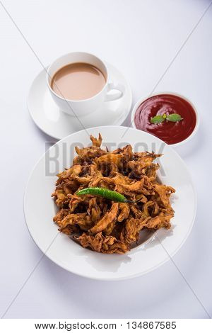 Crispy onion bhaji or kanda bhaji or fried onion pakore or pakode, delicious street food, favourite indian snack in monsoon served with hot tea