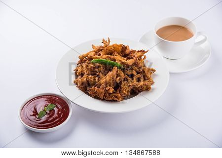 Crispy onion bhaji or kanda bhaji or fried onion pakore or pakode, delicious street food, favourite indian snack in monsoon served with hot tea