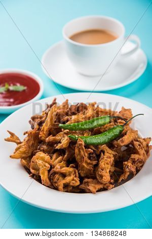 Crispy onion bhaji or kanda bhaji or fried onion pakore or pakode, delicious street food, favourite indian snack in monsoon served with hot tea