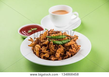 Crispy onion bhaji or kanda bhaji or fried onion pakore or pakode, delicious street food, favourite indian snack in monsoon served with hot tea