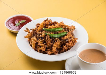 Crispy onion bhaji or kanda bhaji or fried onion pakore or pakode, delicious street food, favourite indian snack in monsoon served with hot tea