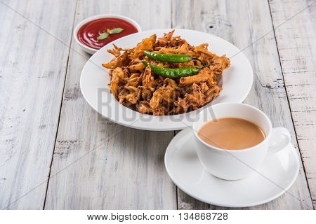 Crispy onion bhaji or kanda bhaji or fried onion pakore or pakode, delicious street food, favourite indian snack in monsoon served with hot tea
