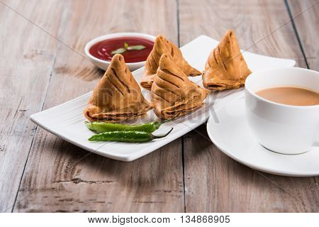 Samosa snack with tomato ketchup and hot tea, Fresh samosas with ketchup and hot chai ready for breakfast