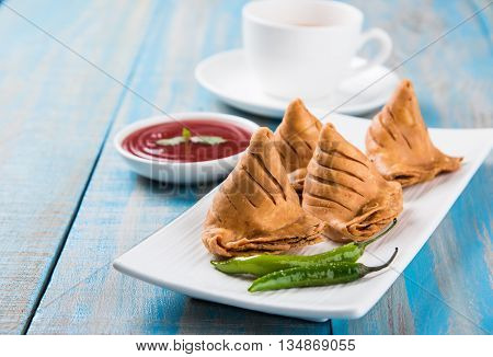 Samosa snack with tomato ketchup and hot tea, Fresh samosas with ketchup and hot chai ready for breakfast