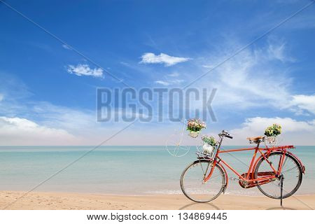 Old red Bicycle with basket flowers on beautiful beach tropical sea background