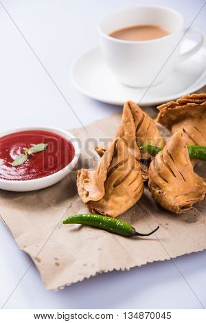 Samosa snack with tomato ketchup and hot tea, Fresh samosas with ketchup and hot chai ready for breakfast
