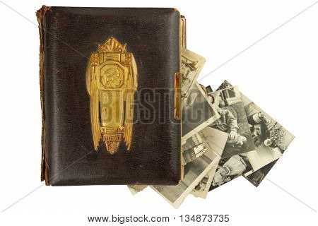 Vintage photo album (circa 1900) with buckle, brass engraved decoration and falling out retro photos (circa 50s) isolated on white