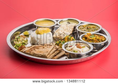 typical maharashtrian food served in plate and bowls made of leaf includes kadhi and shrikhand, plain dal, spinach curry, aalu mutter, plain rice, papad, bhakri or bhakar or roti and variety of salad