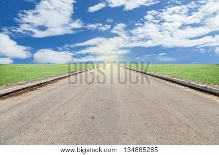 asphalted road with green grass blue sky background