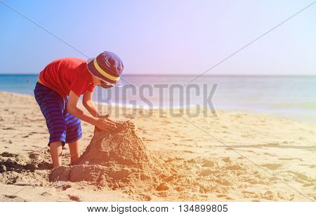 little boy play with sand on summer beach