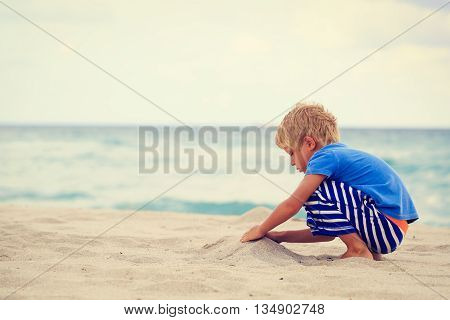 little boy play with sand on summer beach