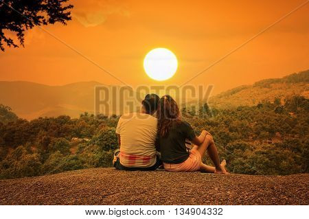 Romantic of couple love sitting on the stone looking sunset at mountain