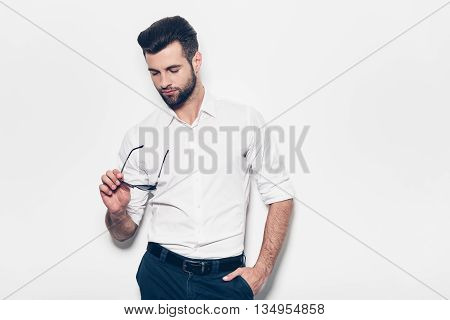 Confident in his style. Handsome young man in white shirt looking at them while standing against white background