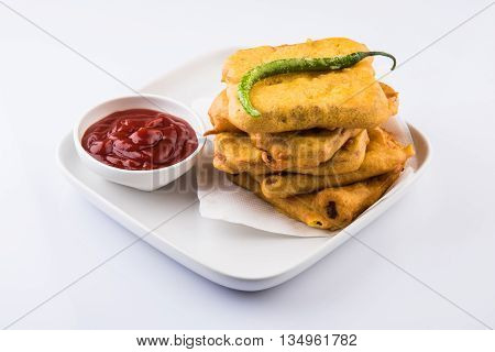 Bread Pakora or bread pakoda served along with tomato ketchup green chilly and onion slices, indian snack