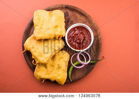 Bread Pakora or bread pakoda served along with tomato ketchup green chilly and onion slices, indian snack