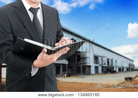 Professional businessman booking with blurred construction factory or warehouse building site background industrial business concept