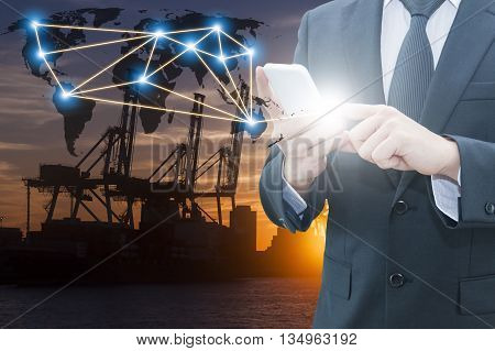 Double exposure of businessman using smart phone network connection world map , transportation port and blurred cargo warehouse background international transportation trading business concept