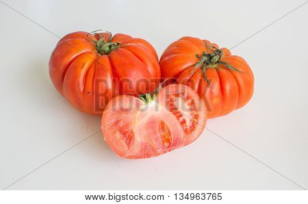 Juicy ripe beefsteak truss tomato fruit isolated on white background with one halved in the foreground