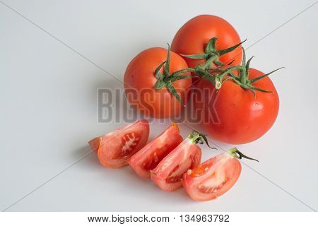 Several ripe truss variety tomato fruit isolated on white background with tomato slices
