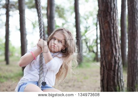 Cute girl on a rope swing at the sea coast