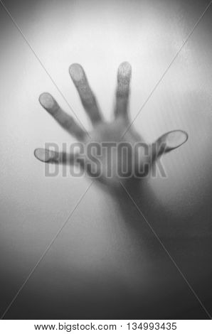 Blurry hand behind matted glass in black and white