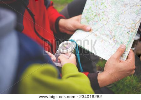 The Boy With His Father Holding A Compass And A Map.