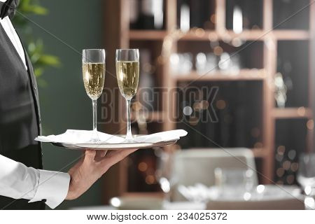Waiter holding tray with glasses of champagne in restaurant