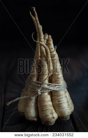 A Bunch Of Parsley Root On A Dark Wooden Table