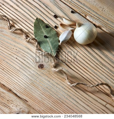 Onion, Garlic, Black Pepper And Bay Leaf On A Wooden Table