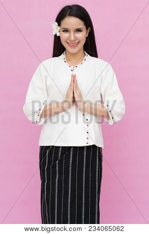 Portrait Of Asian Young Girl In Traditional Thai Dress Praying Isolated On Pink Background. Wai Sawa