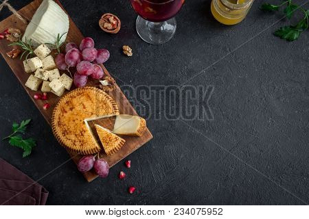 Cheese Platter With Assorted Cheeses, Grapes, Nuts Over Black Background, Copy Space. Italian Cheese