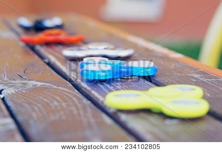 Group Of Fidget Spinner Stress Relieving Toy On Wooden Surface. Selective Focus.