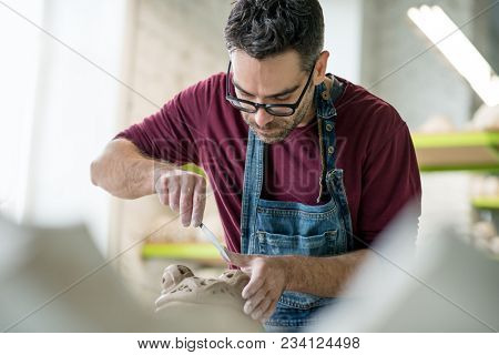Ceramist Dressed in an Apron Sculpting Statue from Raw Clay in the Bright Ceramic Workshop.