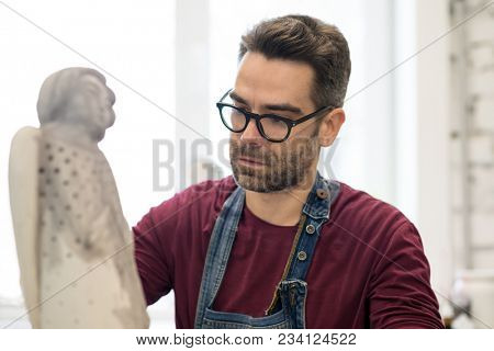 Portrait of Ceramist Dressed in an Apron Working on Clay Sculpture in the Bright Ceramic Workshop.