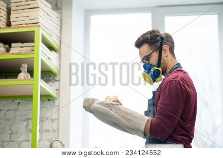 Portrait of Ceramist Dressed in an Apron Working on Clay Sculpture in the Bright Ceramic Workshop.