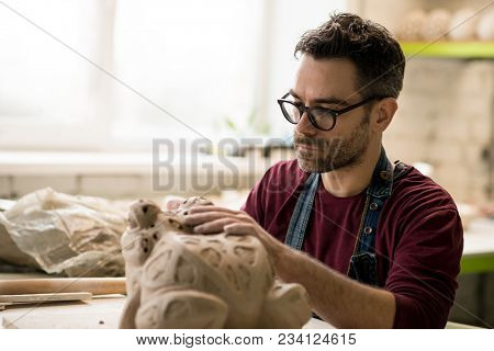 Ceramist Dressed in an Apron Sculpting Statue from Raw Clay in the Bright Ceramic Workshop.