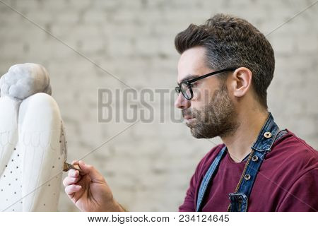 Portrait of Ceramist Dressed in an Apron Working on Clay Sculpture in the Bright Ceramic Workshop.