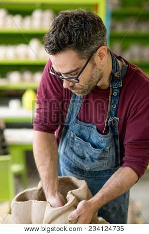 Ceramist Dressed in an Apron Sculpting Statue from Raw Clay in the Bright Ceramic Workshop.