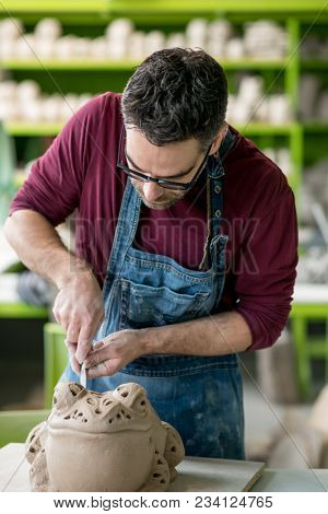 Ceramist Dressed in an Apron Sculpting Statue from Raw Clay in the Bright Ceramic Workshop.
