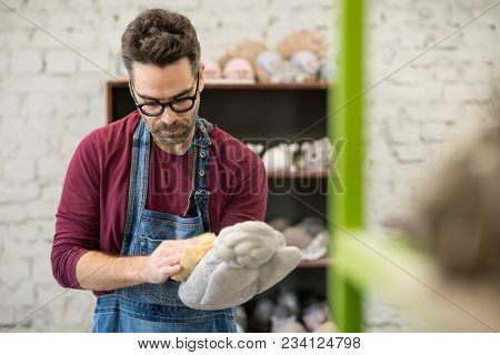 Portrait of Ceramist Dressed in an Apron Working on Clay Sculpture in the Bright Ceramic Workshop.
