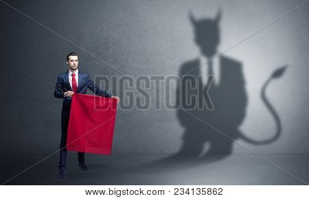 Businessman standing with red cloth in his hand and devil shadow on the background