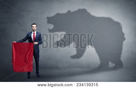 Businessman standing with red cloth in his hand and big bear shadow on his background
