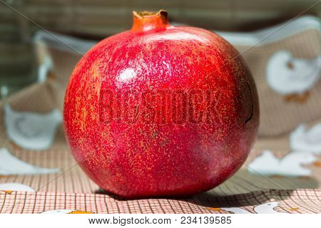 Wholesome Ripe Pomegranate Fruit In Red Scabrous Peel On A Cute Tablecloth.