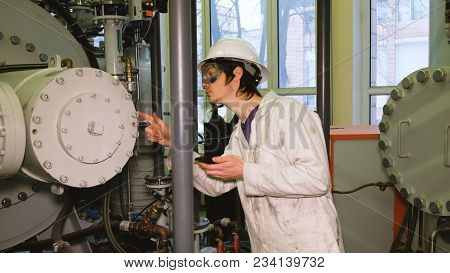 The Technologist In A Protective Helmet And Glasses Makes Inspection Of The Chemical Installation, E